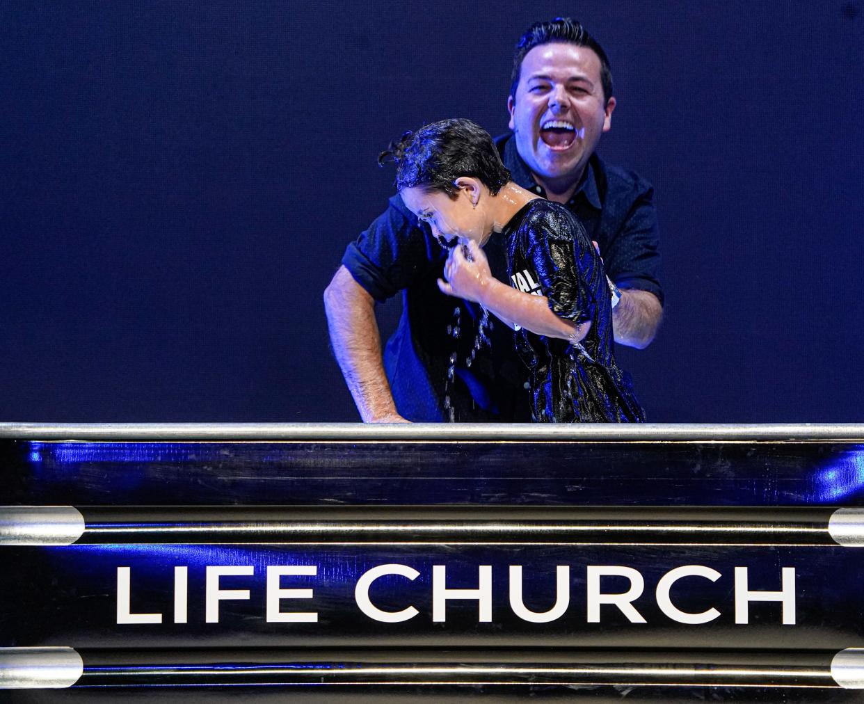 Micah Beckwith, pastor at Life Church gets a laugh while baptizing Greyson Dobbin during a service on Sunday, June 30, 2024, in Noblesville Ind. The young man needed a little comedic coaxing before climbing into what he considered chilly water.