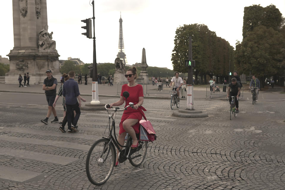 Una mujer cruza en bicicleta el puente Alejandro III en París, el miércoles 13 de septiembre de 2023. (AP Foto/John Leicester)