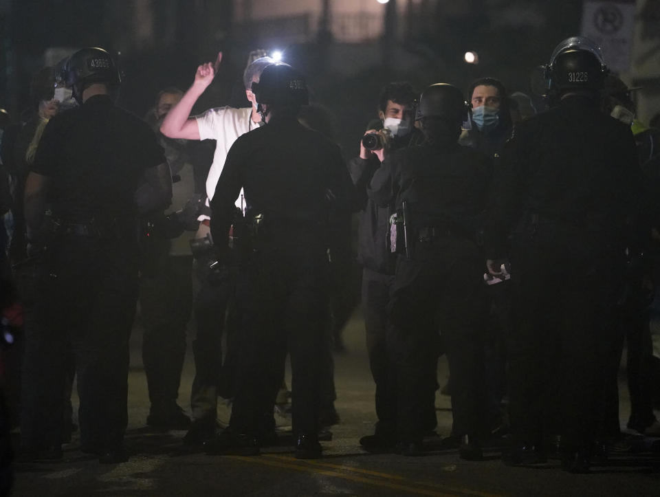 Demonstrators argue with police officers to block the planned temporary closure of the Echo Park Lake homeless encampment which has grown throughout the coronavirus pandemic in Los Angeles late Wednesday, March 24, 2021. (AP Photo/Damian Dovarganes)