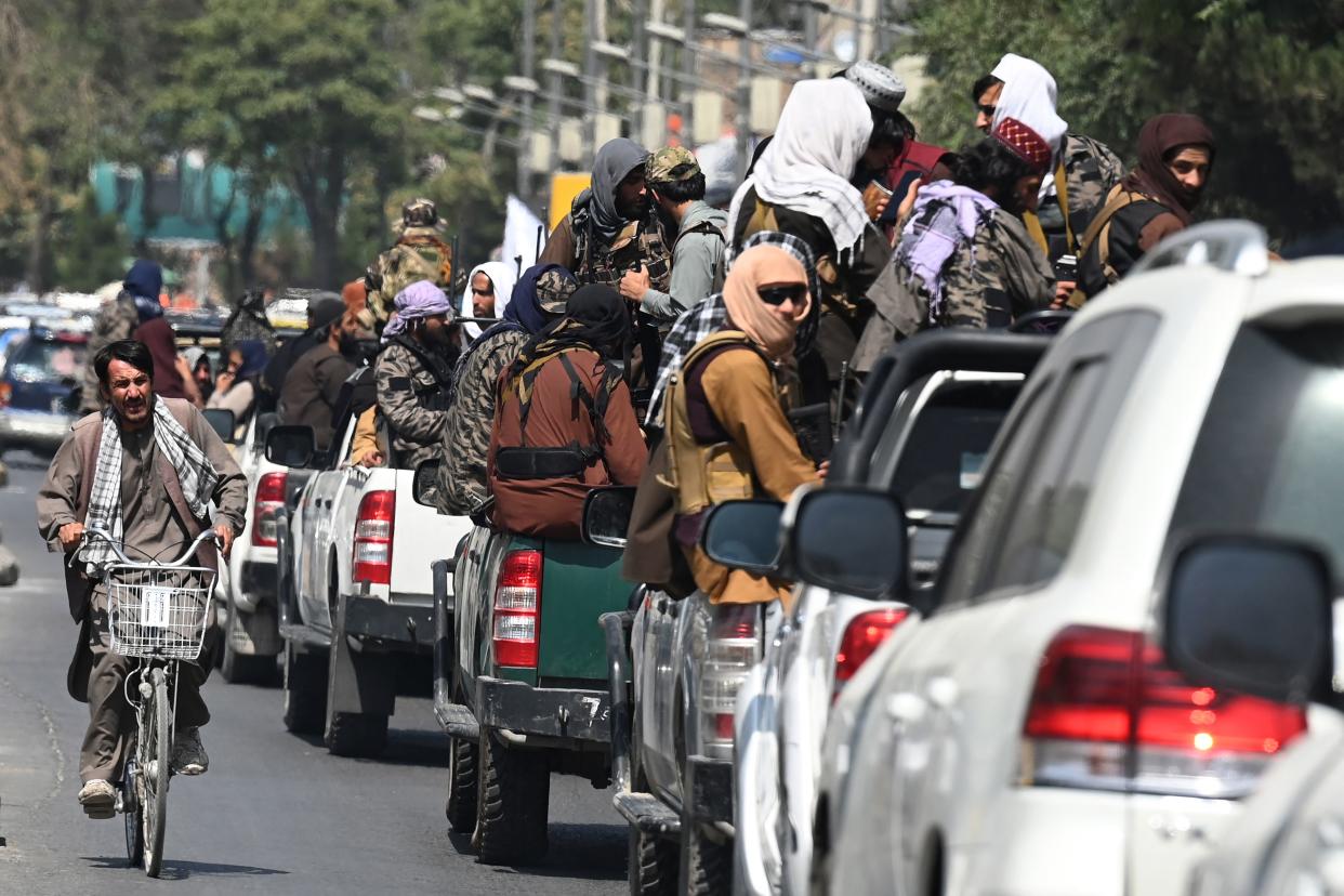 A man on his bicycle rides past a convoy of Taliban fighters patrolling along a street in Kabul on September 2, 2021. (Photo by Aamir QURESHI / AFP) (Photo by AAMIR QURESHI/AFP via Getty Images)