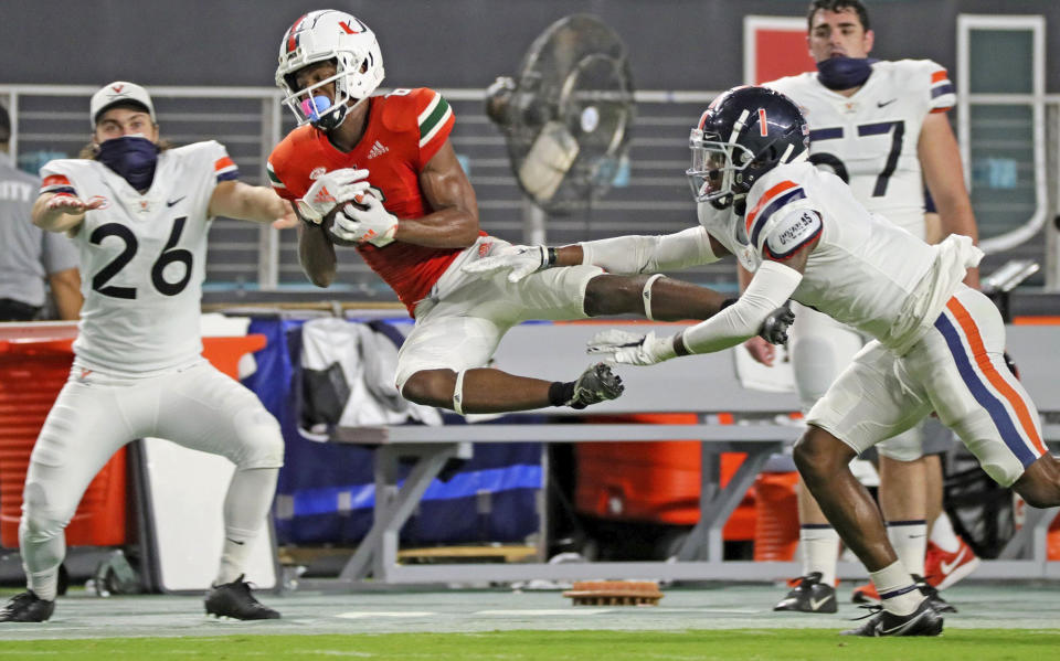 Miami wide receiver Mark Pope (6) catches a first-half pass as Virginia's Nick Grant (1) defends during an NCAA college football game in Miami Gardens, Fla., Saturday, Oct. 24, 2020. (Al Diaz/Miami Herald via AP)