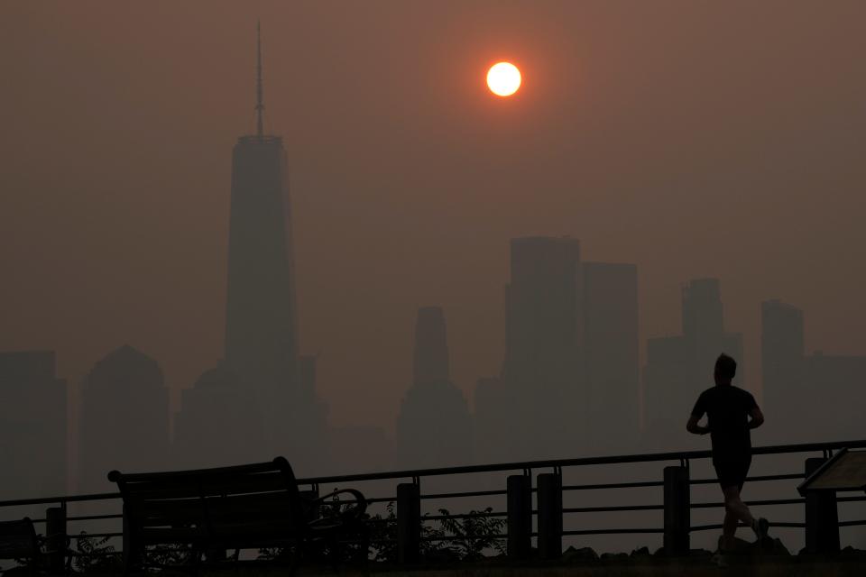 A man runs in front of the sun rising over the lower Manhattan skyline in Jersey City, N.J., June 8, 2023.