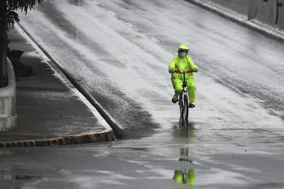 A man wearing a protective mask and raincoat rides his bicycle during rain caused by typhoon Vongfong in Manila, Philippines Philippines on Friday May 15, 2020. More than 150,000 people were riding out a weakening typhoon in emergency shelters in the Philippines on Friday after a mass evacuation that was complicated and slowed by the coronavirus. (AP Photo/Aaron Favila)