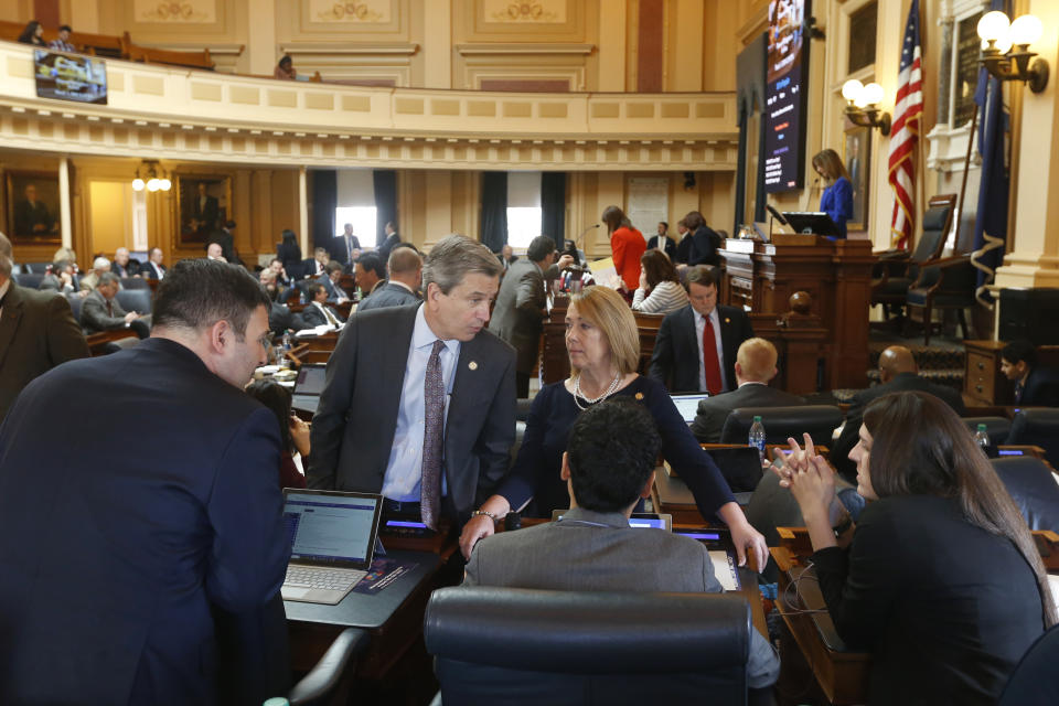 Del. Richard 'Rip' Sullivan, D-Arlington, second from left, talks with Del. Martha Mugler, D-Hampton, center right, and other Delegates during the House session at the Capitol Thursday, March 5, 2020, in Richmond, Va. Sullivan is leading the floor debate on the renewable energy bills. (AP Photo/Steve Helber)