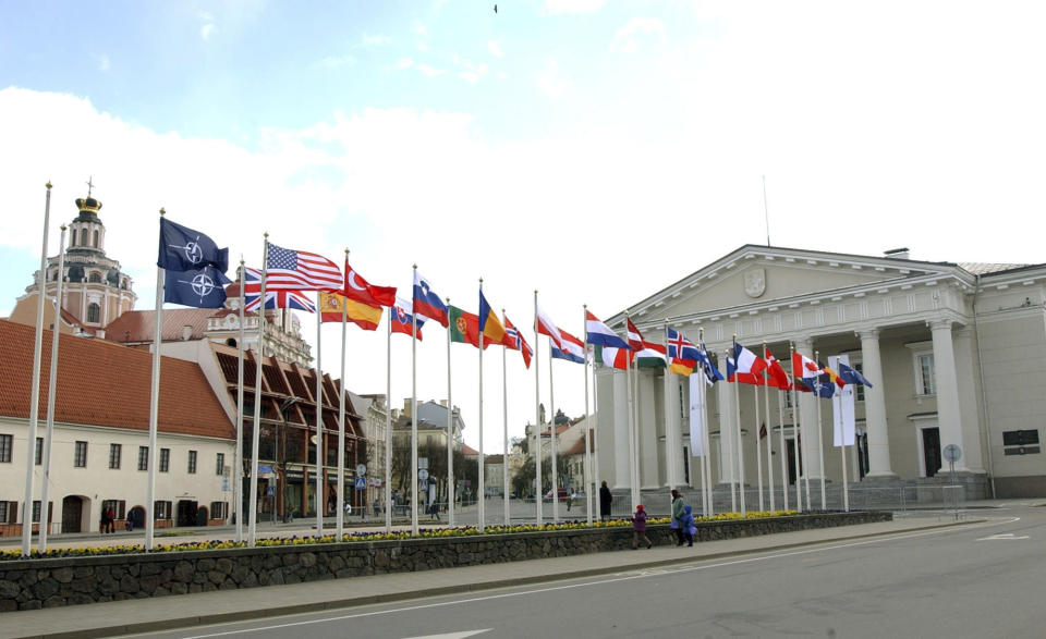 FILE - A woman and her children walk by flags from the NATO nations prior to a meeting of NATO foreign ministers on a main square of the Old Town in Vilnius, Wednesday April 20, 2005. A two-day NATO leaders summit, starting Tuesday, July 11, 2023, with U.S. President Joe Biden and other NATO leaders will be the most high-profile international event that Lithuania has hosted since it joined the alliance in 2004, and some locals hope it will be of historic significance. (AP Photo/Virginia Mayo, File)