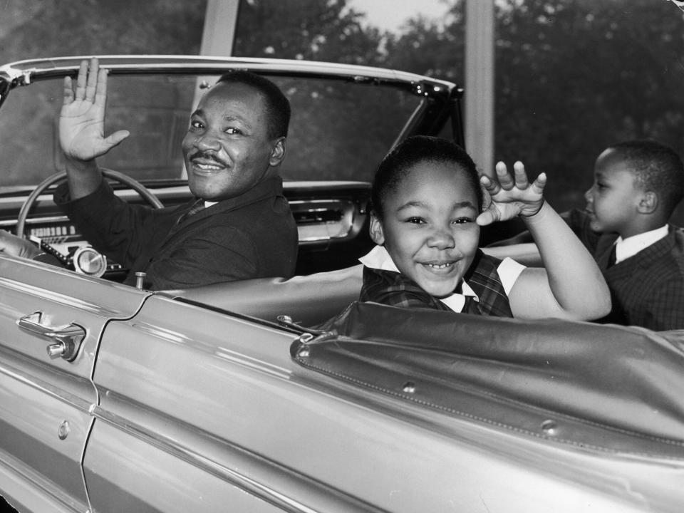 Martin Luther King Jr. (1929 - 1968) waves with his children, Yolanda and Martin Luther III, from the 'Magic Skyway' ride at the Worlds Fair, New York City. The ride was a replica of a Ford convertible