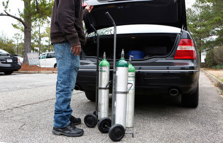 Kwasonte Davis, 25, loads oxygen tanks into his uncle Wardell Davis' car outside his home in Virginia Beach, Virginia, U.S., January 19, 2019. REUTERS/Julia Rendleman