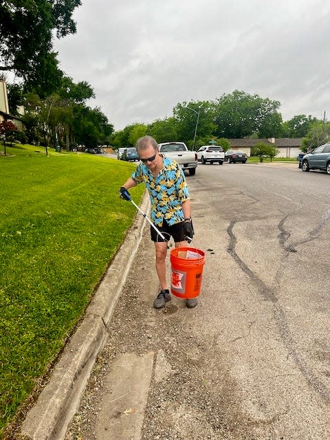 A community member cleans up litter in his neighborhood. Asked his name, he said, "I'm nobody."