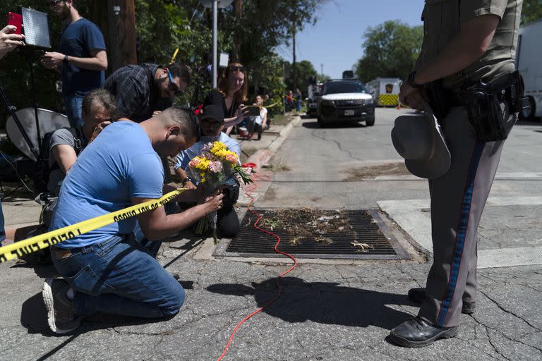 Joseph Avila, a la izquierda, reza mientras sostiene flores en honor a las víctimas de la masacre del martes en la Escuela Primaria Robb, el miércoles 25 de mayo de 2022, en Uvalde, Texas. (AP Foto/Jae C. Hong)