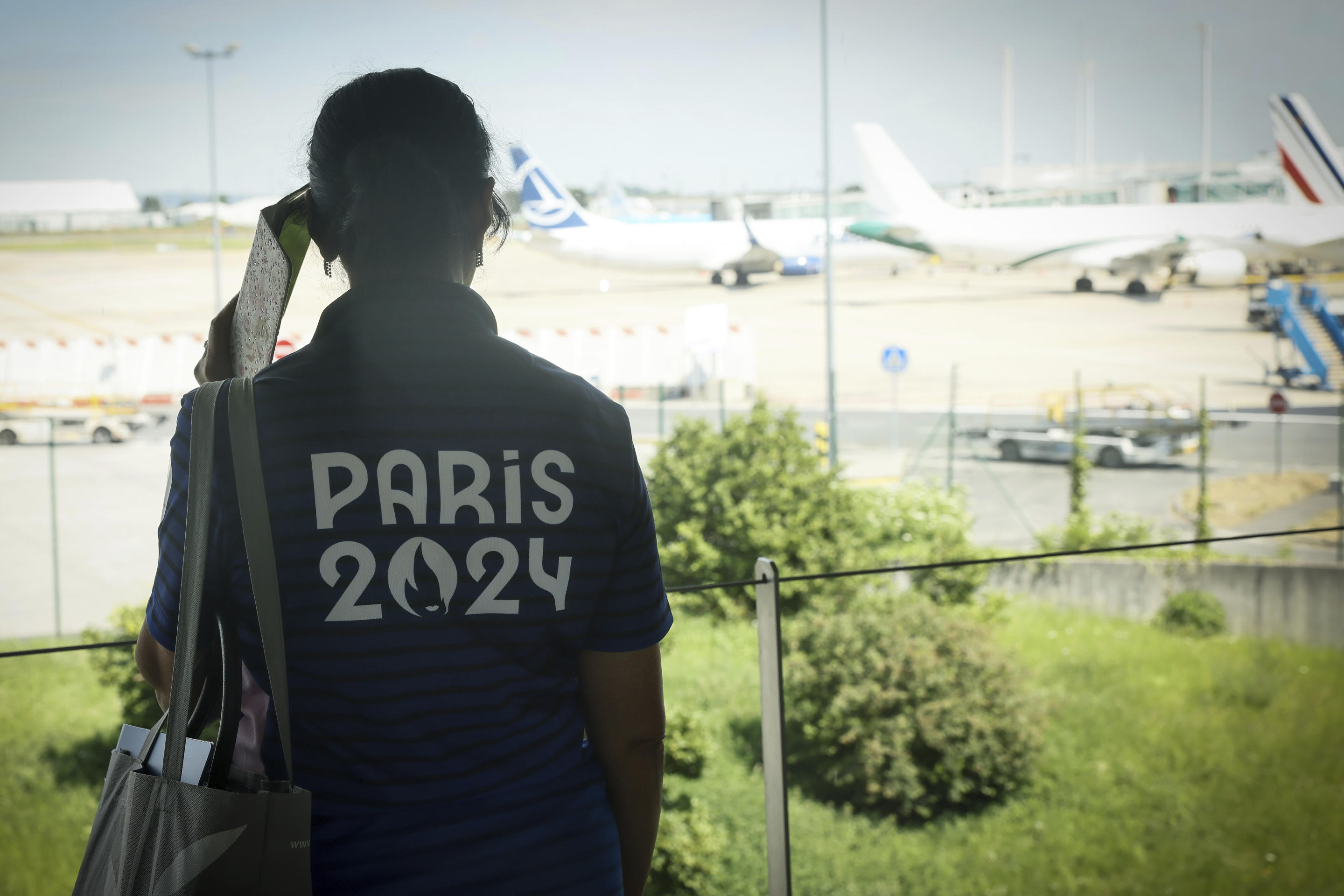 A Paris Olympics volunteer watches planes on the tarmac at Charles de Gaulle airport.