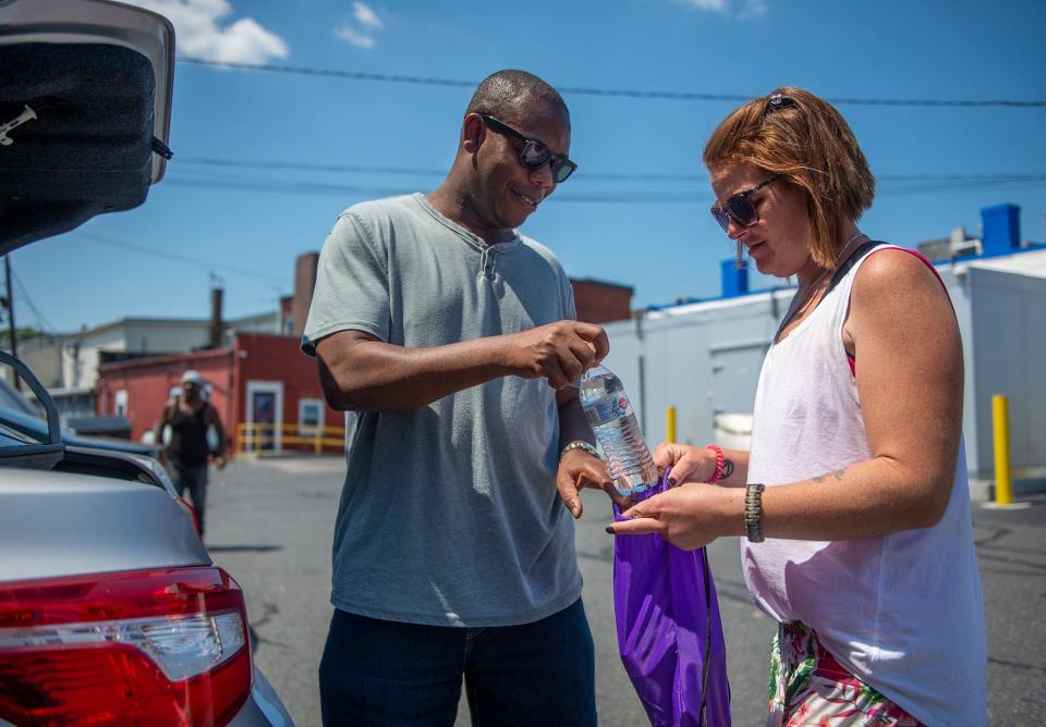 Charley Bokor spent his lunch hour from his job as a program coordinator for the Mass. Dept. of Housing and Community Development handing out water to people in the parking lot of Big Boi Meat Market in downtown Framingham, Aug. 4, 2022. Bokor urges people to remember their fellow citizens, particularly those who are housing challenged, when extreme weather is at hand.