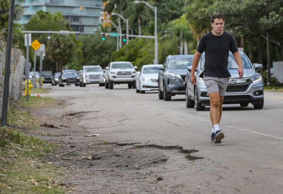 Un peatón camina alrededor del pavimento en ruinas en el popular Commodore Trail a lo largo de la concurrida South Bayshore Drive en Coconut Grove, Miami, lo que lo pone cerca de los coches que se mueven rápidamente. El Condado Miami-Dade está trabajando en un plan de $16 millones para reconstruir un tramo de 1.5 millas de Bayshore y el sendero. Los críticos dicen que el mal diseño del sendero, las condiciones de deterioro y la velocidad del tráfico suponen un peligro para los usuarios.