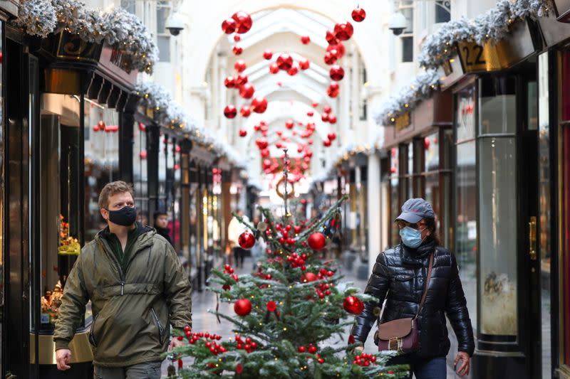 People walk through the Burlington Arcade adorned with Christmas decorations, in London