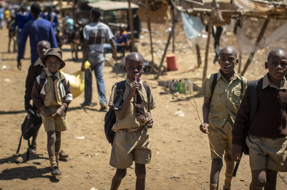 A schoolboy sucks on a lollipop as he and his friends walk back home on the first day of the school term, in Kuwadzana, on the outskirts of the capital Harare, in Zimbabwe Tuesday, Sept. 10, 2019. Former president Robert Mugabe, who enjoyed strong backing from Zimbabwe's people after taking over in 1980 but whose support waned following decades of repression, economic mismanagement and allegations of election-rigging, is expected to be buried on Sunday, state media reported. (AP Photo/Ben Curtis)