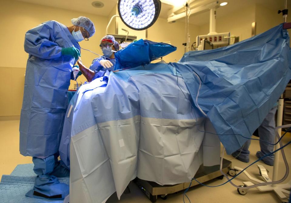 Dr. Myron Hall, left, operates on Glory Paschal's right foot in South L.A.