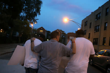 Father Michael Pfleger (C) speaks with participants in a weekly night-time peace march through the streets of a South Side neighborhood in Chicago, Illinois, September 16, 2016. REUTERS/Jim Young