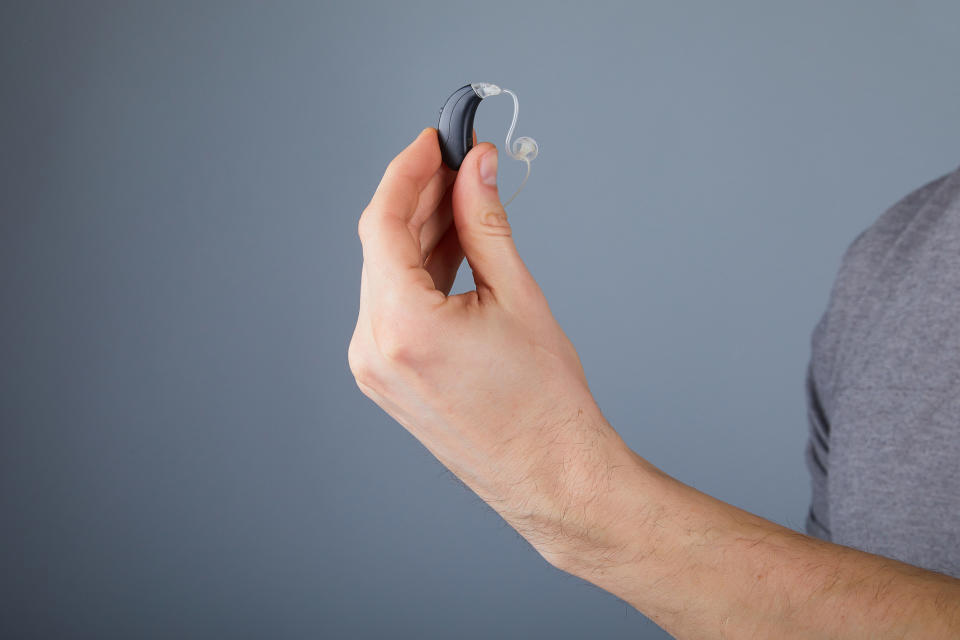 A stock image of a person holding a hearing aid