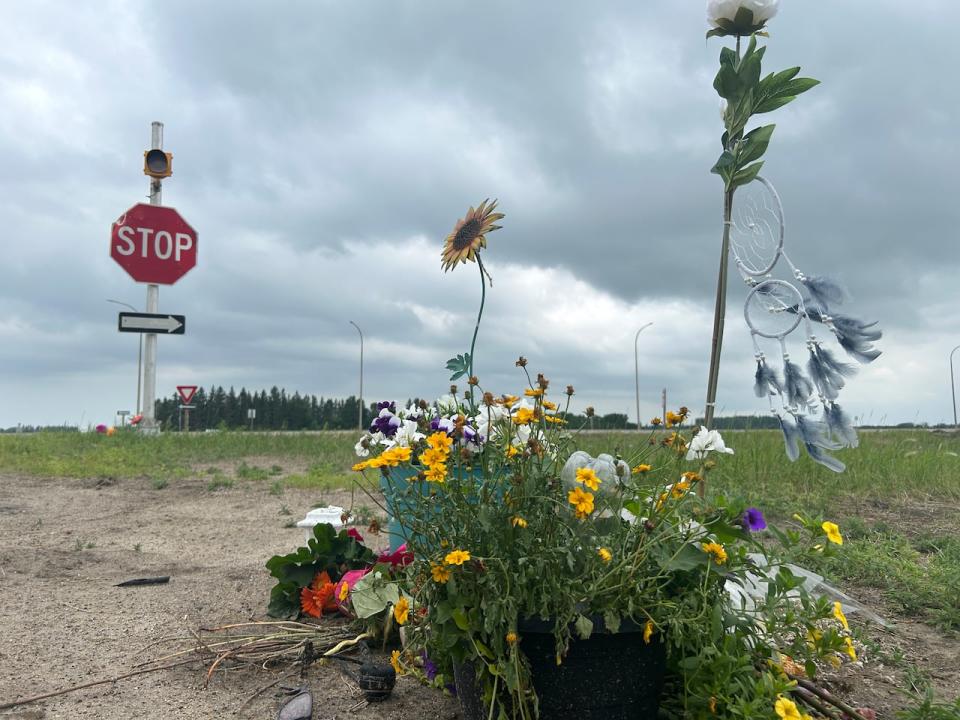 A makeshift memorial was set up near a highway intersection north of Carberry, Man., after a fatal collision there between a semi-trailer truck and a bus full of seniors on a day trip to a casino in June 2023.  (Gilbert Rowan/CBC - image credit)