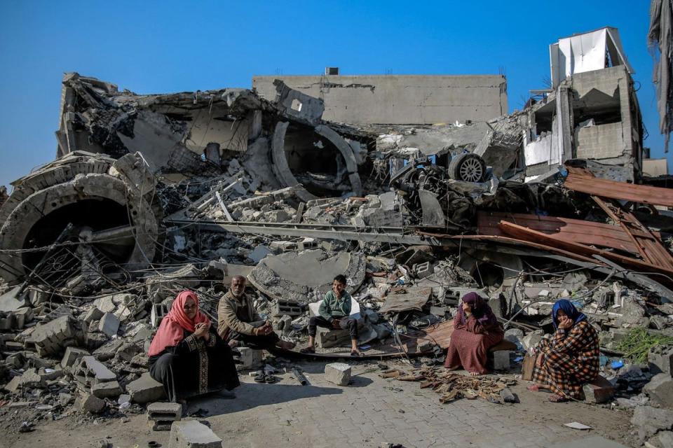 Palestinians sit next to a building destroyed during Israeli strikes in Gaza City on February 26 (AFP via Getty Images)