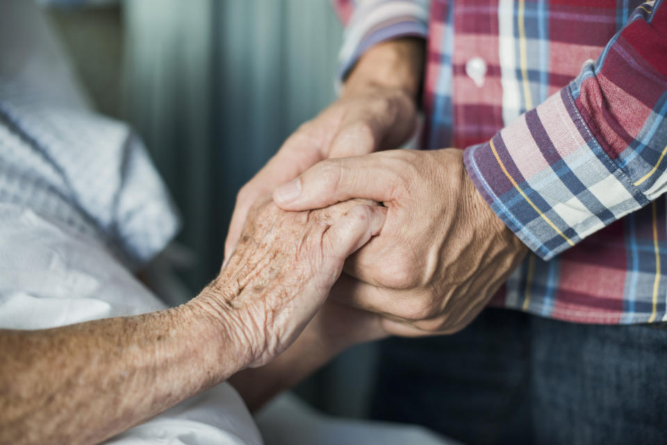 Close up of son holding his mothers hands in hospitla