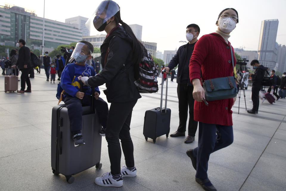 Passengers wearing face masks and face shields to protect against the spread of coronavirus gather outside of Hankou train station after of the resumption of train services in Wuhan in central China's Hubei Province, Wednesday, April 8, 2020. After 11 weeks of lockdown, the first train departed Wednesday morning from a re-opened Wuhan, the origin point for the coronavirus pandemic, as residents once again were allowed to travel in and out of the sprawling central Chinese city. (AP Photo/Ng Han Guan)