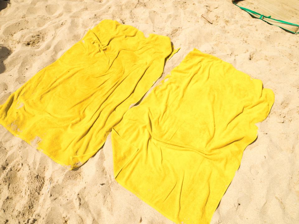 Two yellow beach towels laid out on the sand