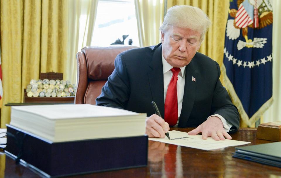 PHOTO: President Donald Trump signs a tax-overhaul bill into law in the Oval Office of the White House, Dec. 22, 2017.  (Mike Theiler/Pool via Bloomberg via Getty Images)