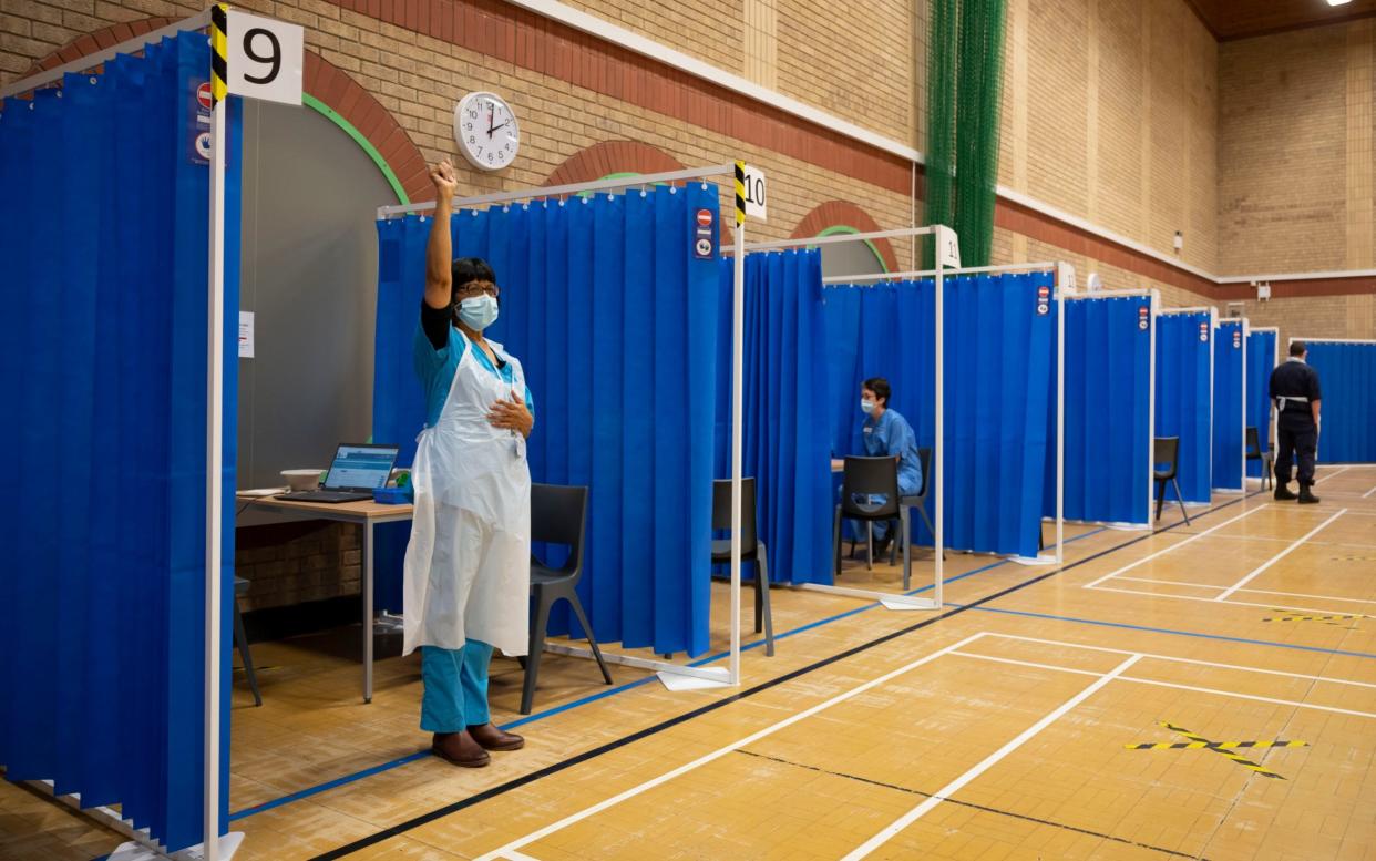 A health worker signals to a colleague that she is available to administer a vaccine at a mass Covid vaccination centre in Barry, South Wales - Matthew Horwood/Getty Images Europe