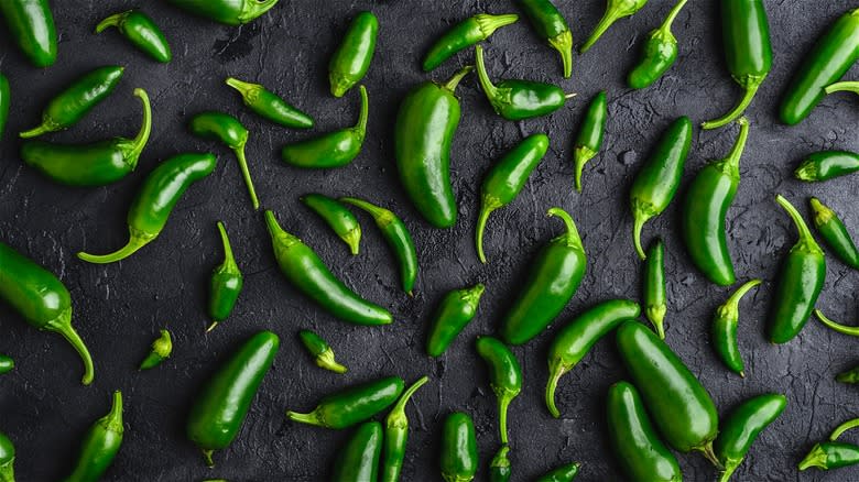 Whole jalapeño peppers on black background