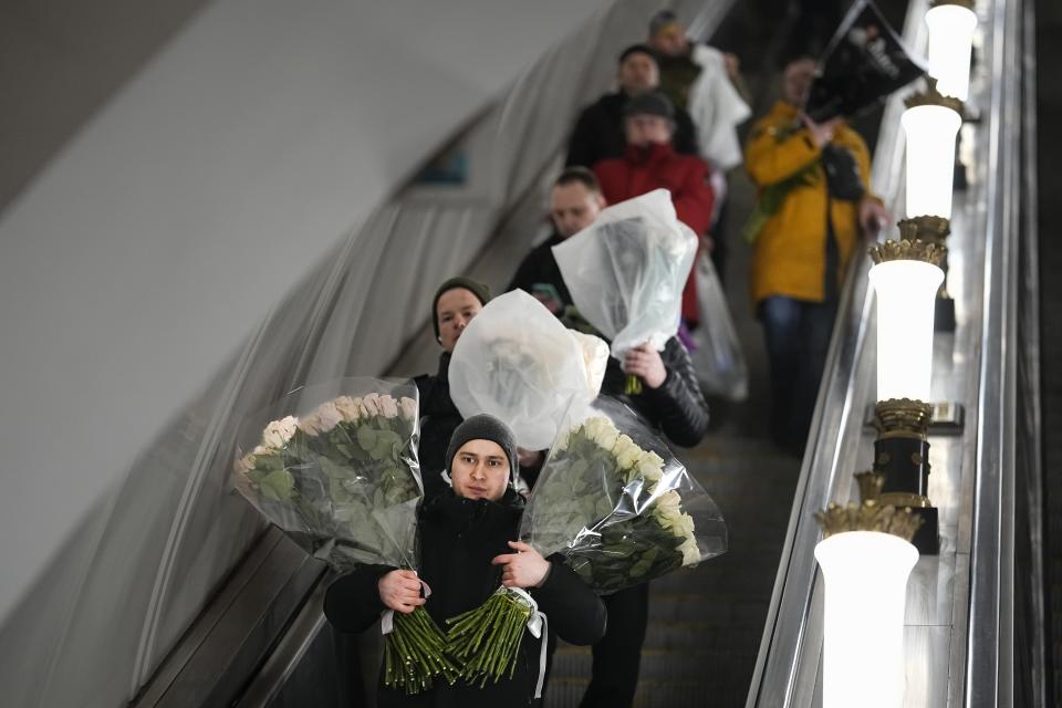 A man goes down the escalator in the subway holding bunches of flowers purchased from the flower market on International Women's Day, in Moscow, Russia, early Friday, March 8, 2024. International Women's Day on March 8 is an official holiday in Russia. Per tradition, men give flowers and gifts to female relatives, friends and colleagues, even though in the past two years flowers have gotten more expensive. (AP Photo/Alexander Zemlianichenko)