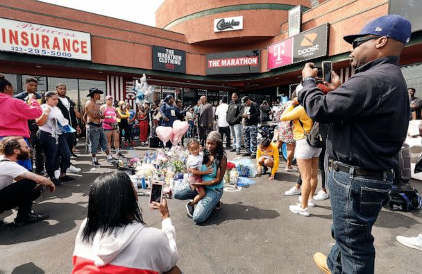 PHOTO: Mourners and supporters take photos as they gather at a growing memorial in front of The Marathon Clothing store, April 1, 2019, in Los Angeles, where rapper Nipsey Hussle was killed and two others wounded outside his store the day prior. (Los Angeles Times via Getty Images, FILE)