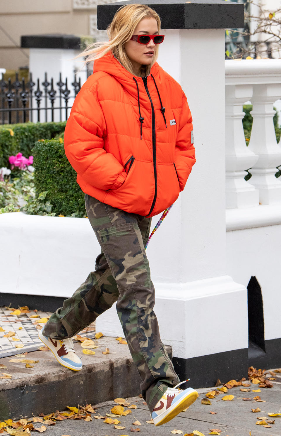 <p>Rita Ora wears a bright orange puffer coat and camo pants while leaving her home in London on Monday.</p>