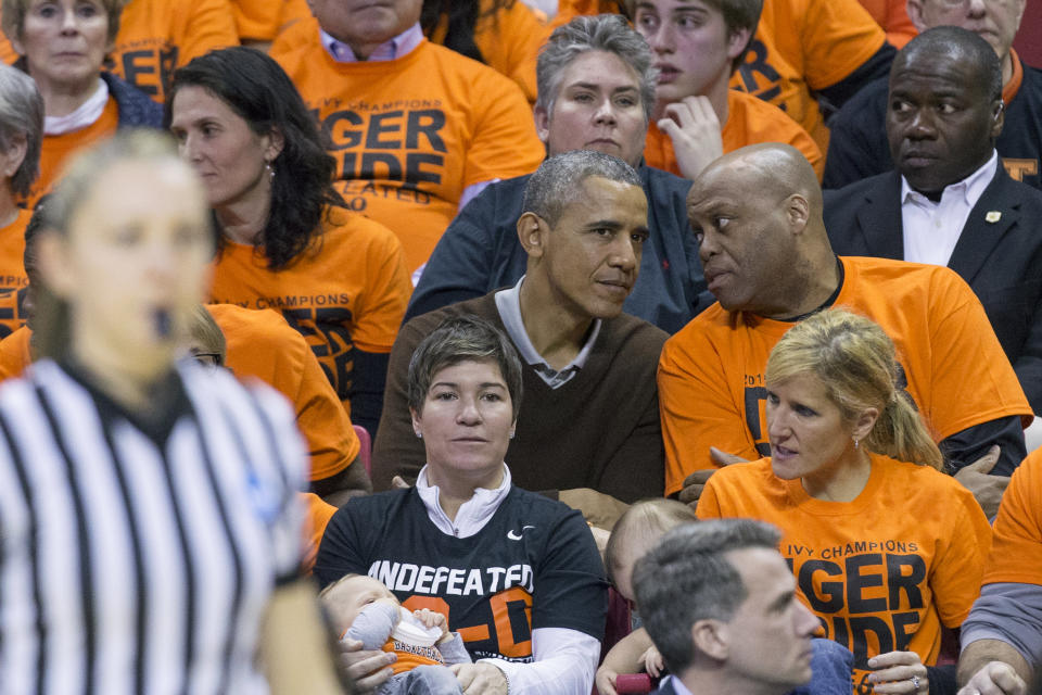 President Barack Obama (left) sits beside his brother-in-law Craig Robinson while attending the Green Bay versus Princeton women's college basketball game in the first round of the NCAA tournament, March 21, 2015, in College Park, Maryland. President Barack Obama's niece Leslie Robinson plays for Princeton.