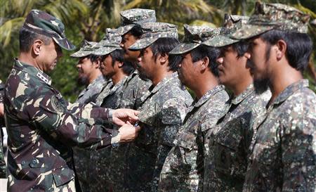 Philippine marines who are deployed for five months aboard the BRP Sierra Madre, a military detachment on the disputed Second Thomas Shoal, part of the Spratly Islands in the South China Sea, receive Bronze medals from Western Command chief Lt Gen Roy Deveraturda (L) at a naval forces camp in Palawan province, southwest Philippines March 31, 2014. REUTERS/Erik De Castro