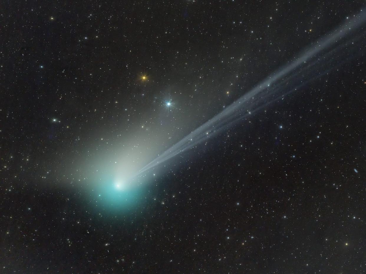 green comet streaking across starry night sky with long white tail