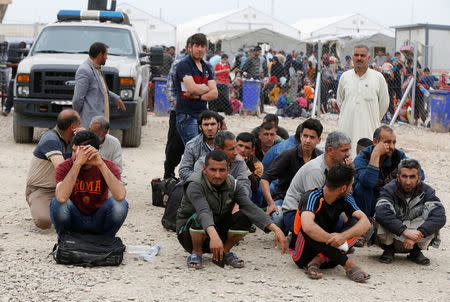 Displaced Iraqi men who fled their homes during a battle between Iraqi forces and Islamic State militants, wait for a security check at Hammam al-Alil camp checkpoint south of Mosul, Iraq April 18, 2017. REUTERS/Muhammad Hamed