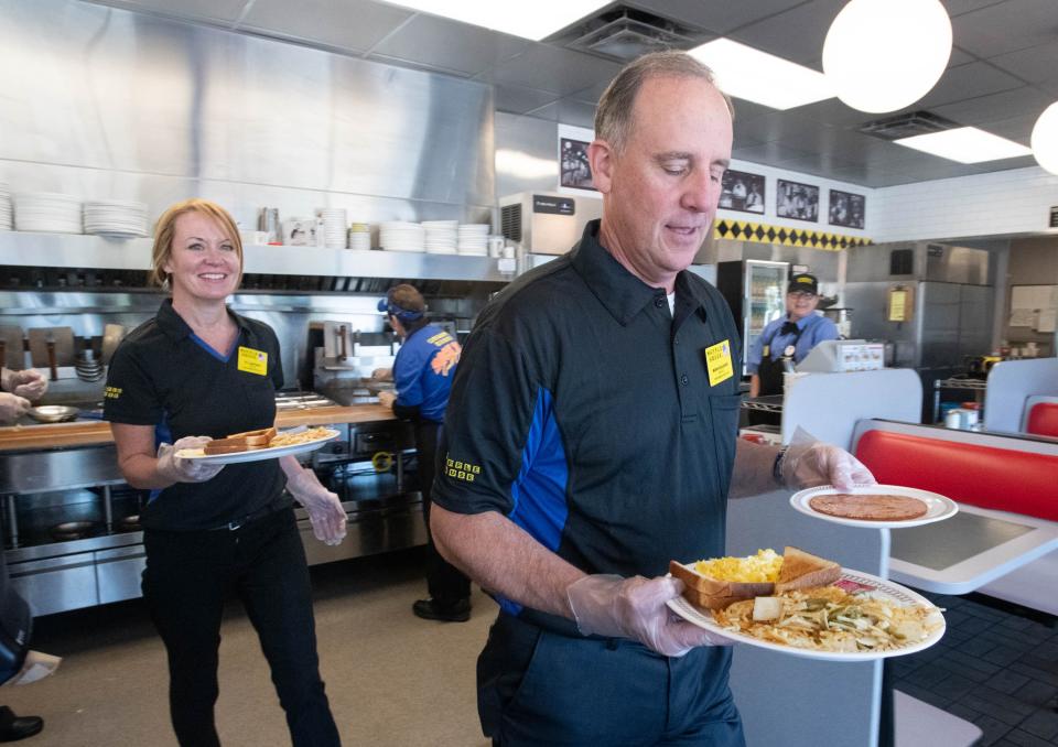 KC Gartman, Baptist Health Care chief development officer, left, and Mark Faulkner, Baptist Health Care CEO, deliver an order to a table at the Waffle House on Brent Lane in Pensacola on Wednesday, Oct. 18, 2023.