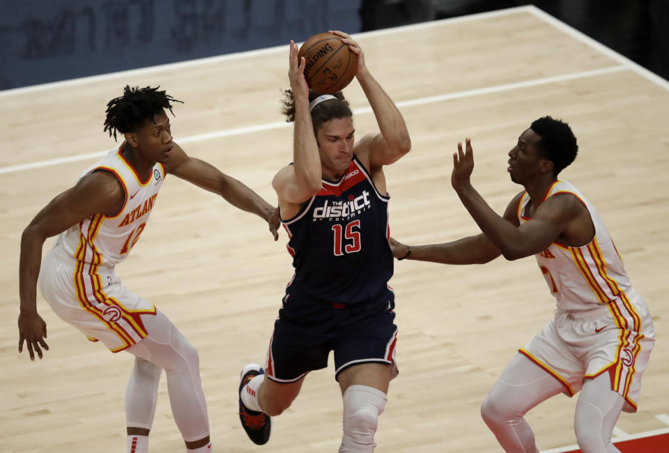 Washington Wizards' Robin Lopez, center, drives the ball between Atlanta Hawks' De'Andre Hunter, left, and Onyeka Okongwu, right, during the first half of an NBA basketball game Monday, May 10, 2021, in Atlanta. (AP Photo/Ben Margot)