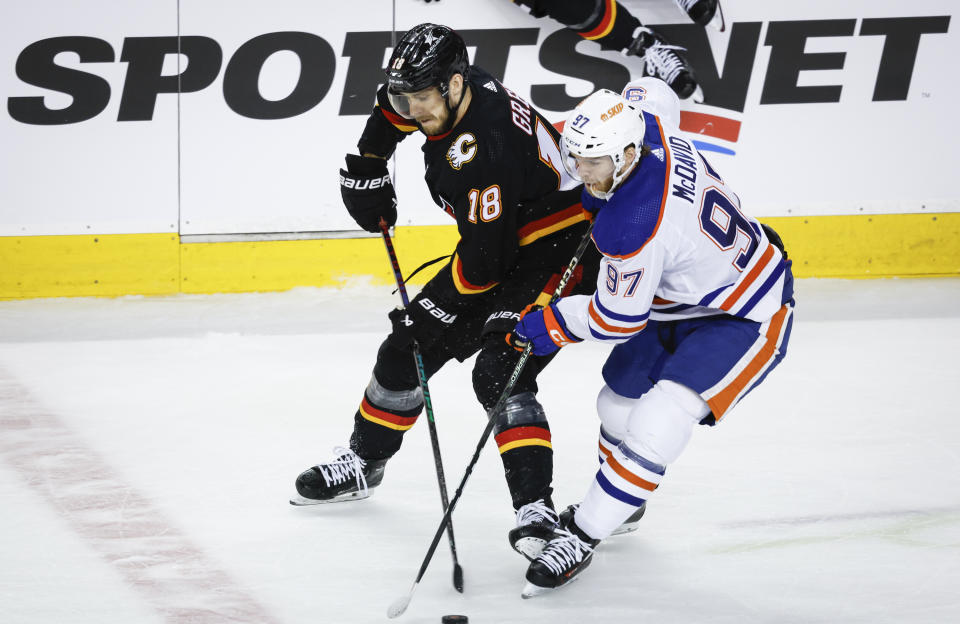 Edmonton Oilers forward Connor McDavid (97) steals the puck from Calgary Flames forward A.J. Greer (18) during the first period of an NHL hockey game Saturday, April 6, 2024, in Calgary, Alberta. (Jeff McIntosh/The Canadian Press via AP)