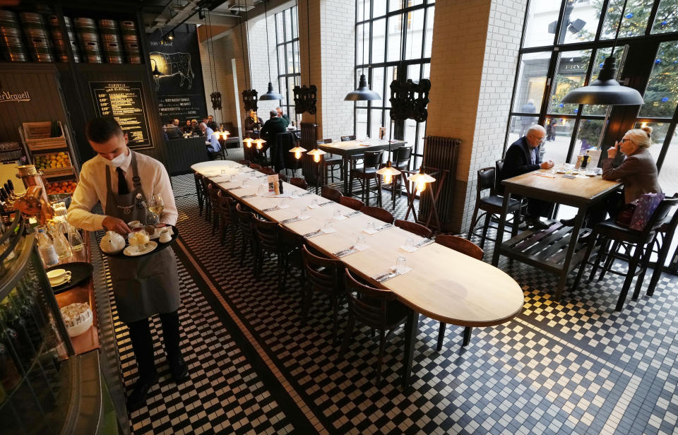 A server at the "Der Elefant" restaurant prepares drinks and food on a tray, in Warsaw, Poland, Tuesday Dec. 7, 2021. Der Elefant is the first and until recently the only restaurant in Poland to require proof of vaccination to dine. The requirement is a norm in Western Europe, but not in Poland, where many people are hesitant about vaccines and the government has resisted imposing vaccine mandates until announcing Tuesday that health workers, teachers and police and other uniformed service workers will need to be vaccinated against COVID-19 by March. (AP Photo/Czarek Sokolowski)