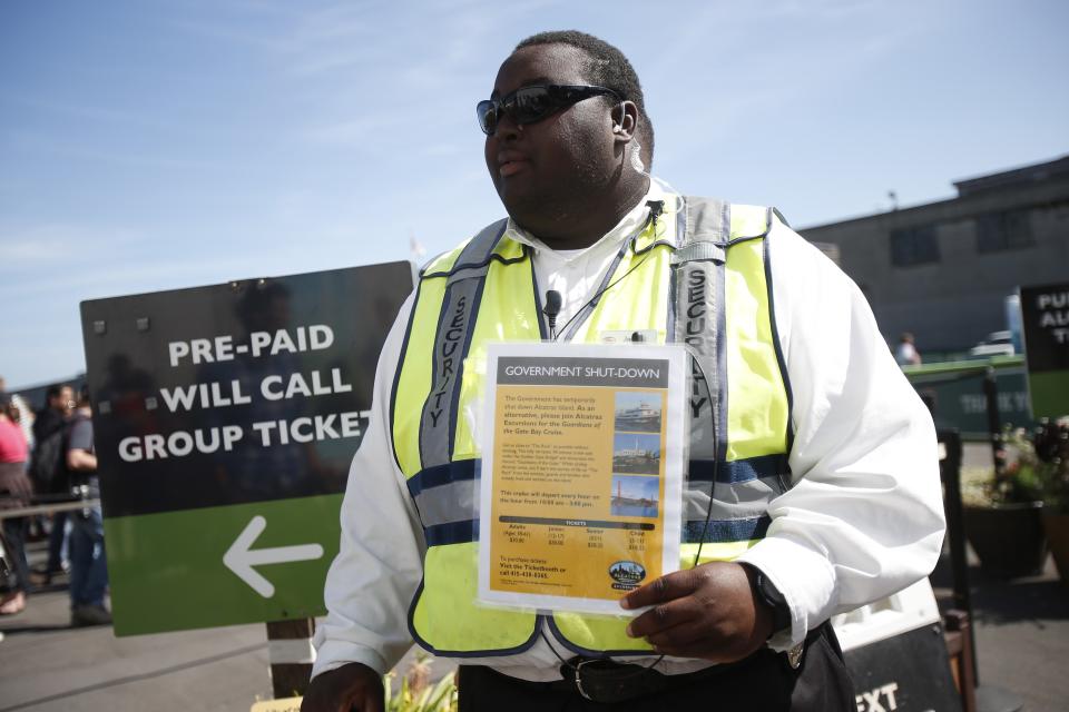 Security officer Jarvis Landlum holds a sign informing people on the government shutdown of Alcatraz Island, a tourist attraction operated by the National Park Service, in San Francisco, California October 1, 2013. The White House rejected a Republican plan to reopen portions of the U.S. government on Tuesday as the first shutdown in 17 years closed landmarks like the Statue of Liberty and threw hundreds of thousands of federal employees out of work. REUTERS/Stephen Lam (UNITED STATES - Tags: POLITICS TRAVEL BUSINESS)