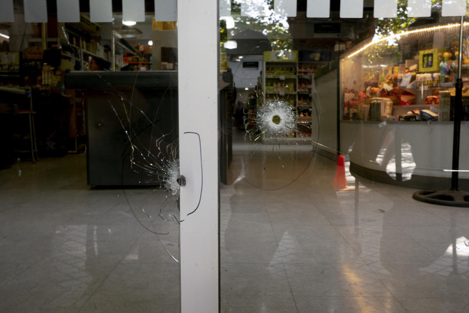 Bullets holes crack the windows of the Unico supermarket, a grocery chain owned by soccer player Lionel Messi's in-laws, in Rosario, Argentina, Thursday, March 2, 2023. (AP Photo/Sebastian Lopez Brach)