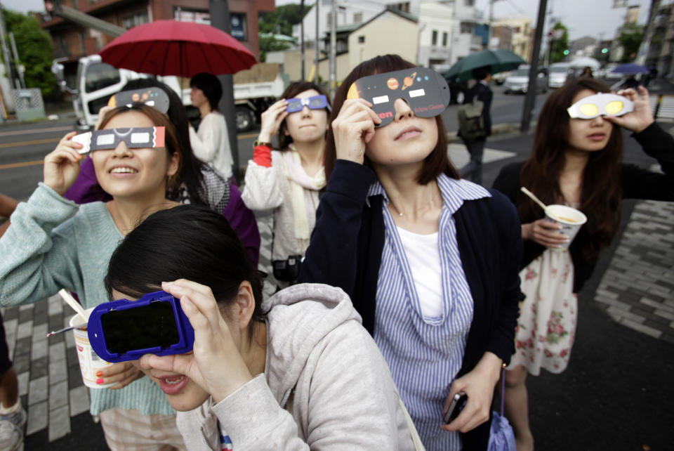 FILE - In this May 21, 2012 file photo, people watch the annular solar eclipse in Fujisawa, near Tokyo. The first solar eclipse of the year happens Tuesday, April 29, 2014, and will be visible to skygazers in Antarctica, Australia, and the southern Indian Ocean about 0600 GMT (2 a.m. EDT). The eclipse Tuesday is a rare type of annular eclipse, meaning the sun will appear as a ring around the moon. (AP Photo/Shizuo Kambayashi, File)