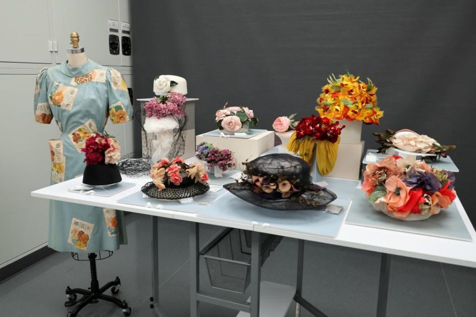 A display of various artistic hats and headpieces with floral and sculptural designs on tables