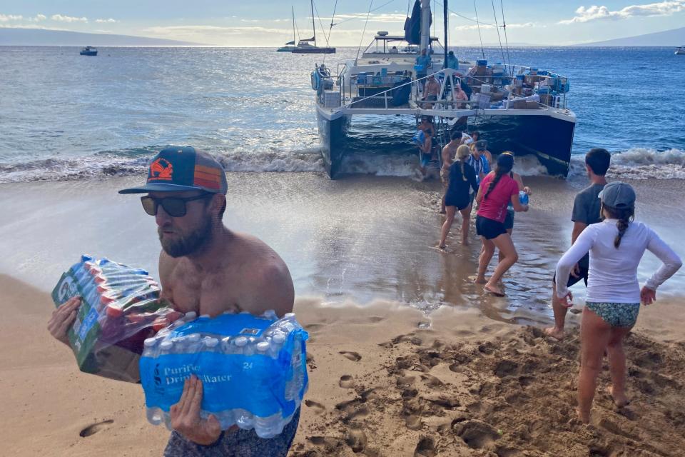 A group of volunteers who sailed from Maalaea Bay, Maui, form an assembly line on Kaanapali Beach (Copyright 2023 The Associated Press. All rights reserved.)