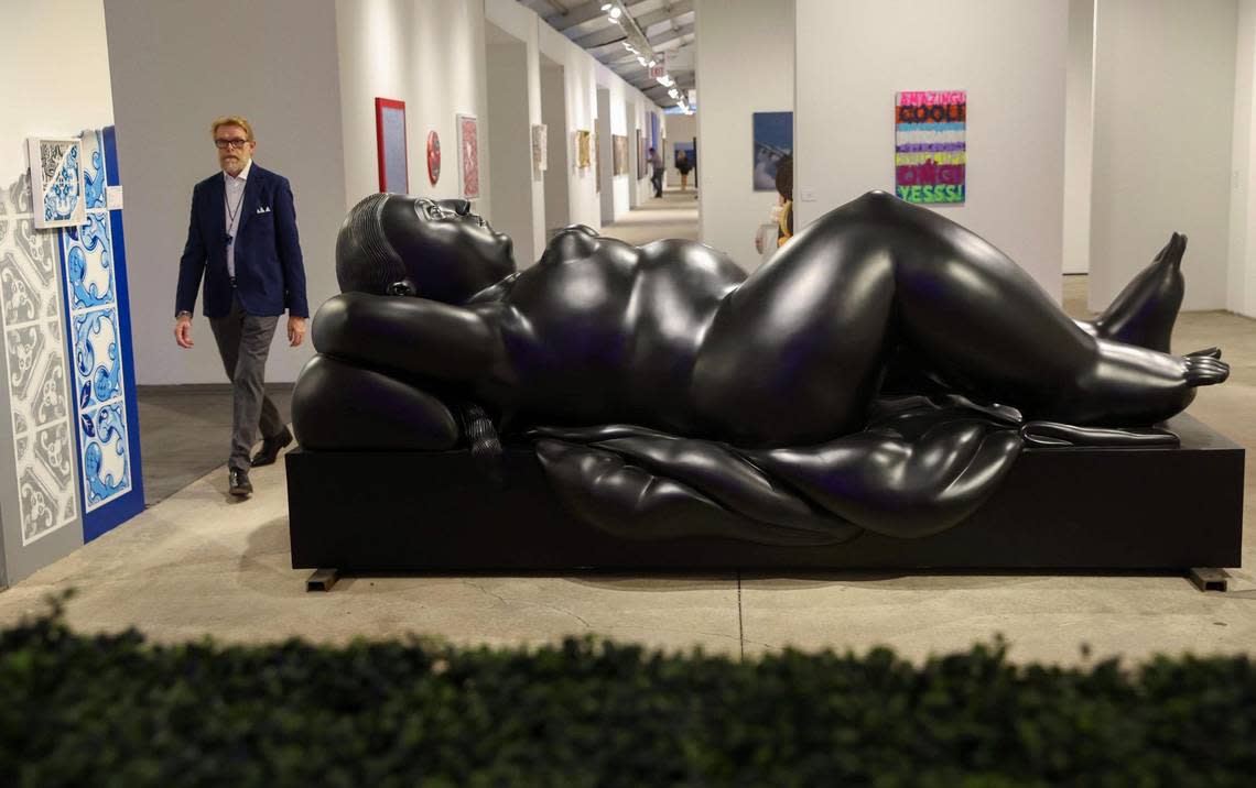 A man makes his way past “Donna Sdraiata” by Fernando Botero on display at Art Miami, which opened Tuesday.