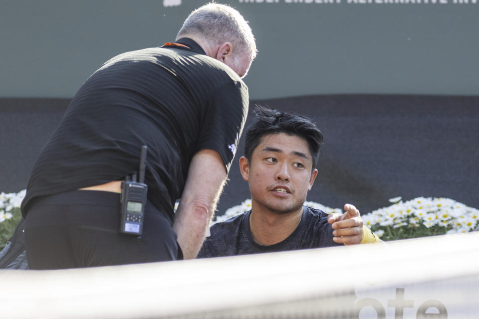 Yibing Wu of China discusses with the doctor before giving up on injury, during his quarter-final match against Germany's Alexander Zverev at the Geneva Open tennis tournament in Geneva, Switzerland, Thursday, May 25, 2023. (Martial Trezzini/Keystone via AP)