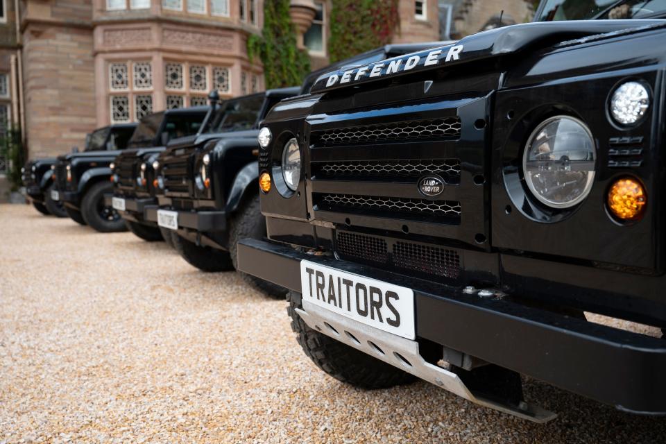 Close up of Traitors printed on front of black cars in front of castle on The Traitors