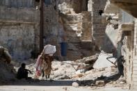 A woman walks on debris of damaged buildings in Aleppo's Sheikh Maqsoud neighbourhood, Syria July 15, 2017. REUTERS/Omar Sanadiki