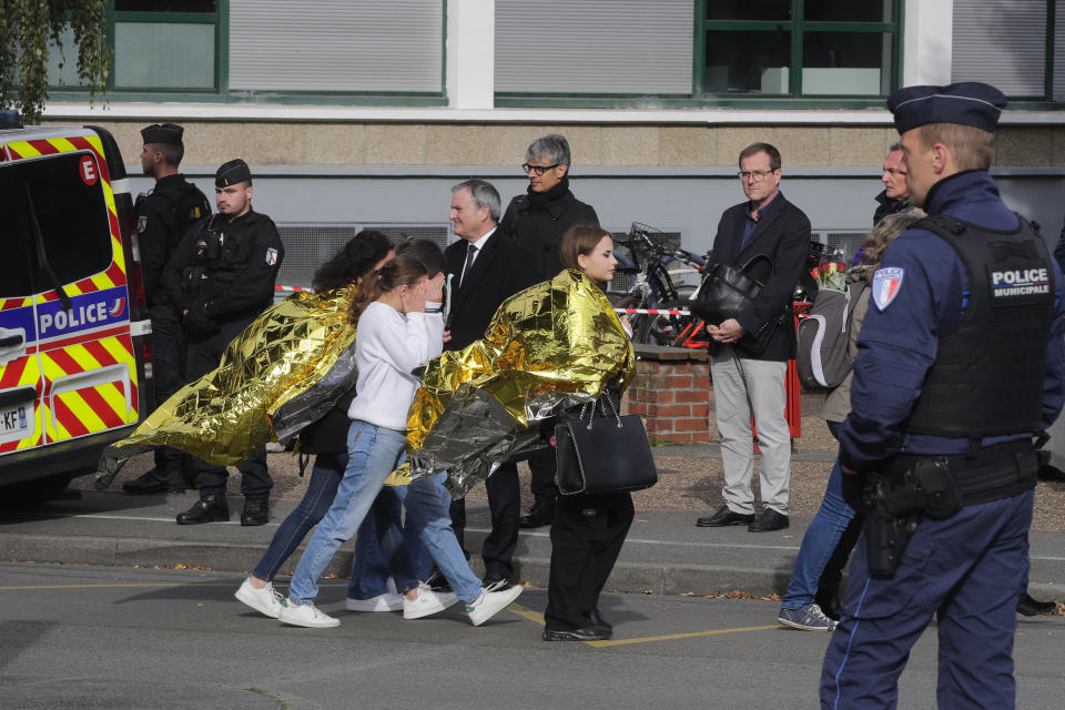 Police officers escort children outside the Gambetta high school during a bomb alert Monday, Oct. 16, 2023 in Arras, northern France. French authorities say the high school where a teacher was fatally stabbed in an attack last week has been evacuated over a bomb alert, as France's President cut short travel plans abroad to host a security meeting Monday.(AP Photo/Michel Spingler)